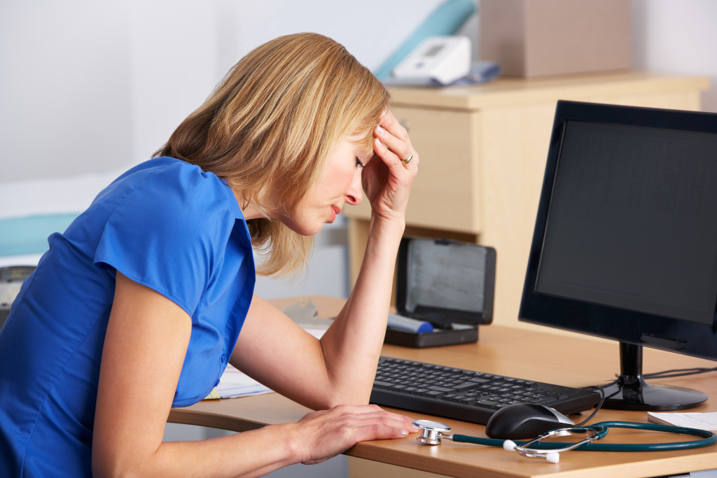 A General Practitioner with head in hand looking stressed and overworked